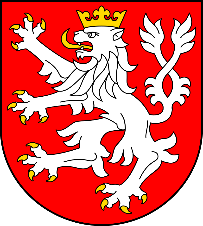 Herb Gminy Lądek Zdrój - Czerwona tarcza ze srebrnym stojącym na tylnych łapach lwem w złotej koronie z rozdwojonym ogonem.